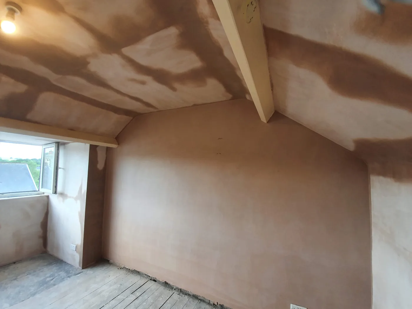 Freshly plastered attic bedroom walls and sloping ceiling after damp treatment, ready to dry out